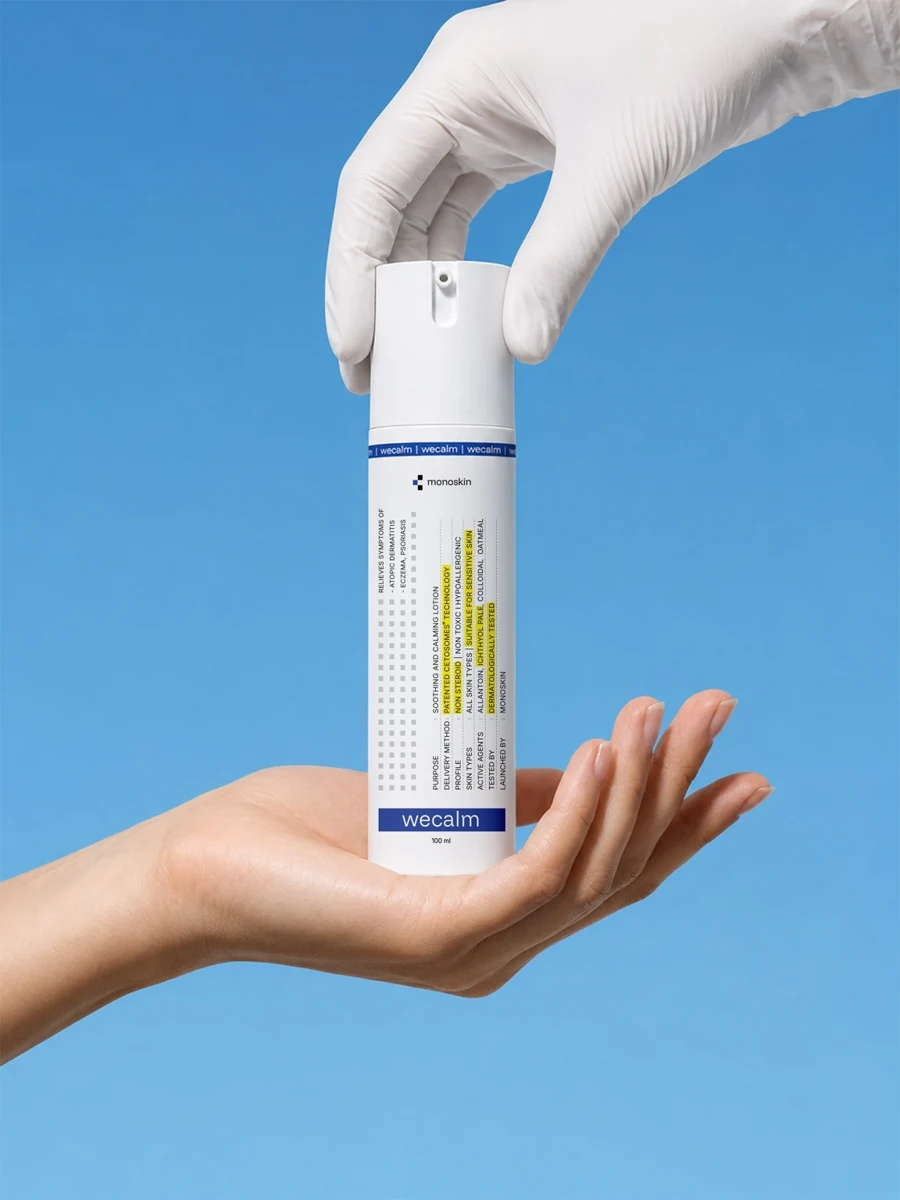 WECALM bottle held between a bare hand and a gloved hand against blue